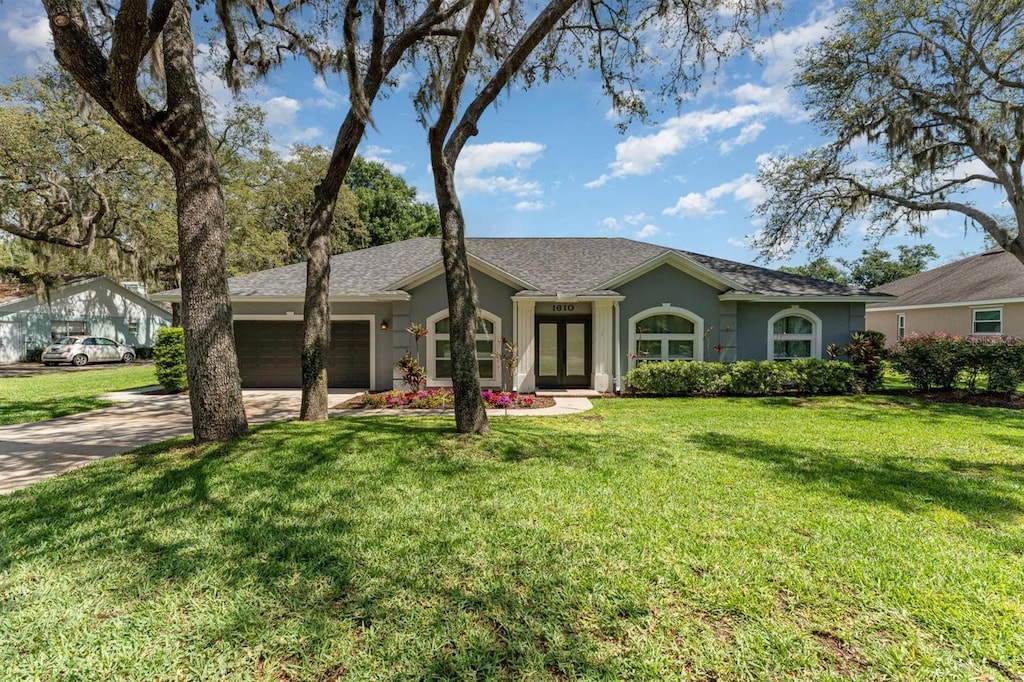 1610 Sherwood Lakes Blvd, Lakeland, FL 33809 - ranch-style home featuring a garage, french doors, concrete driveway, stucco siding, and a front lawn
