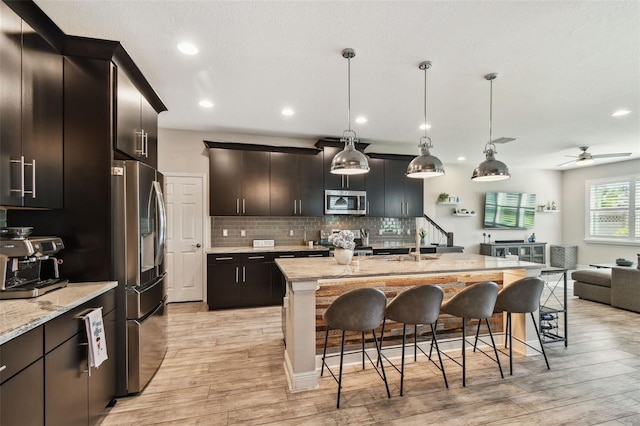 11519 Crowned Sparrow Ln, Tampa, FL 33626 - kitchen with stainless steel appliances, a kitchen breakfast bar, light wood finished floors, open floor plan, and recessed lighting