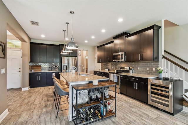 11519 Crowned Sparrow Ln, Tampa, FL 33626 - kitchen featuring stainless steel appliances, beverage cooler, light wood finished floors, backsplash, and a breakfast bar