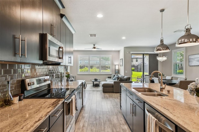 11519 Crowned Sparrow Ln, Tampa, FL 33626 - kitchen with appliances with stainless steel finishes, light wood-type flooring, light stone countertops, open floor plan, and decorative light fixtures