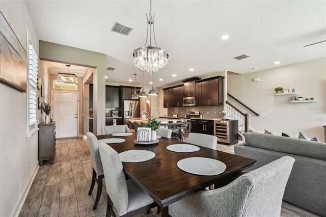 11519 Crowned Sparrow Ln, Tampa, FL 33626 - dining area featuring a chandelier, stairs, light wood finished floors, recessed lighting, and wine cooler