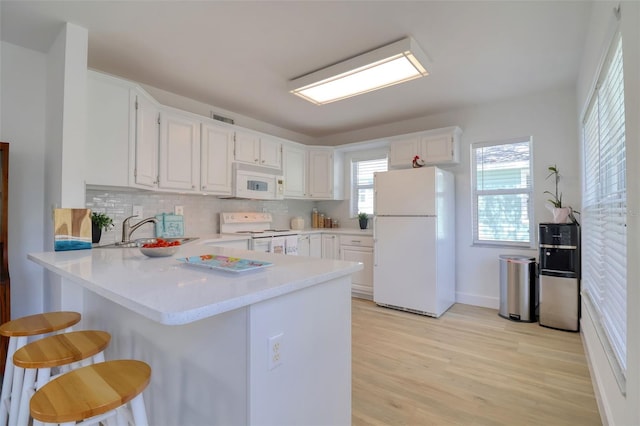 408 Georgia Ave, Crystal Beach, FL 34681 - kitchen featuring white appliances, a peninsula, light countertops, light wood finished floors, and white cabinetry