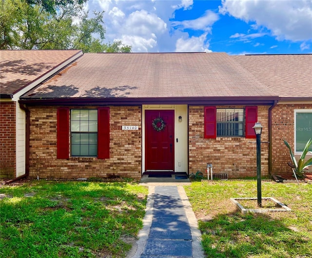 35140 Whispering Oaks Blvd, Dade City, FL 33523 - view of front of home with brick siding, roof with shingles, and a front yard