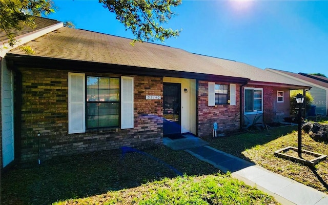 35140 Whispering Oaks Blvd, Dade City, FL 33523 - view of front facade with brick siding and a shingled roof