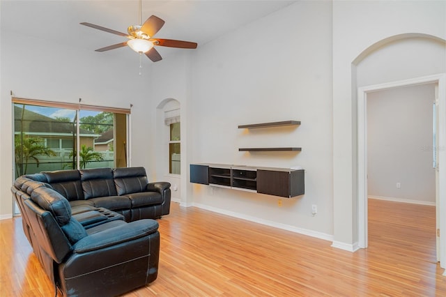 12721 Avelar Creek Dr, Riverview, FL 33578 - living area with arched walkways, light wood finished floors, high vaulted ceiling, and a ceiling fan