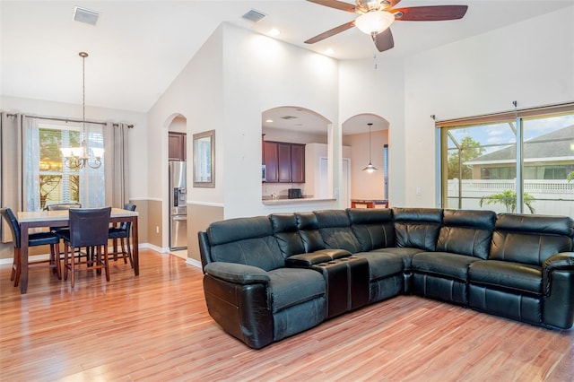 12721 Avelar Creek Dr, Riverview, FL 33578 - living room featuring a chandelier, a ceiling fan, light wood-style floors, high vaulted ceiling, and arched walkways