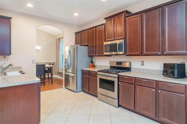 12721 Avelar Creek Dr, Riverview, FL 33578 - kitchen featuring appliances with stainless steel finishes, arched walkways, light tile patterned flooring, light countertops, and recessed lighting