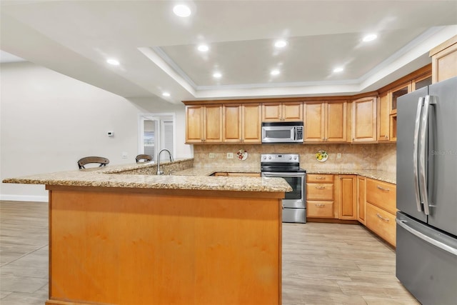 910 Kingscote Ct, Safety Harbor, FL 34695 - kitchen featuring stainless steel appliances, a raised ceiling, tasteful backsplash, a peninsula, and recessed lighting