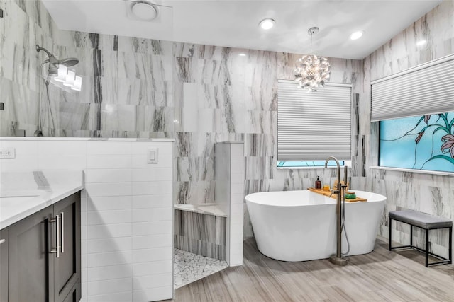 910 Kingscote Ct, Safety Harbor, FL 34695 - full bath featuring a marble finish shower, a freestanding bath, vanity, tile walls, and wood finished floors