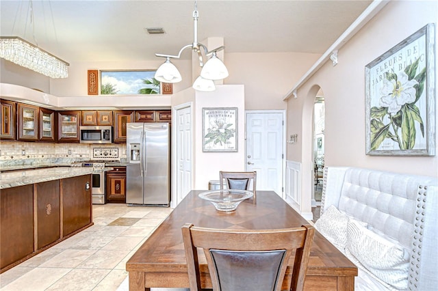 19307 Wind Dancer St, Lutz, FL 33558 - kitchen with stainless steel appliances, arched walkways, glass insert cabinets, decorative backsplash, and light stone counters