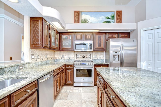 19307 Wind Dancer St, Lutz, FL 33558 - kitchen with stainless steel appliances, decorative backsplash, glass insert cabinets, light stone countertops, and brown cabinetry