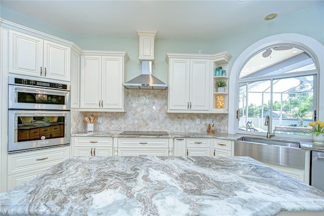 2504 Oak Landing Dr, Brandon, FL 33511 - kitchen featuring stainless steel double oven, light stone countertops, black electric stovetop, white cabinetry, and tasteful backsplash