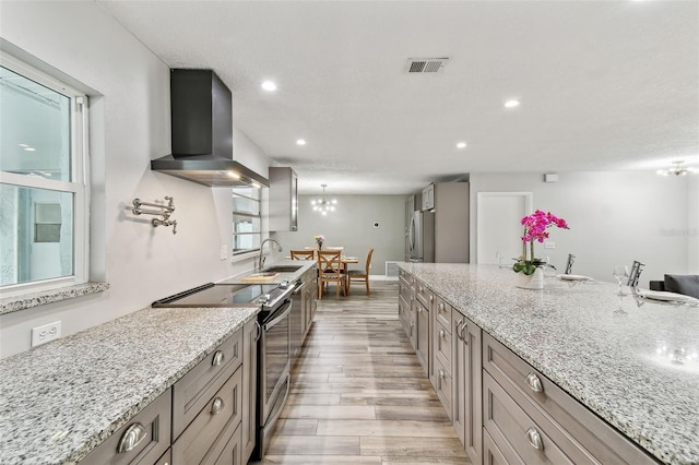 446 Eagle Cir, Casselberry, FL 32707 - kitchen with wall chimney range hood, appliances with stainless steel finishes, light wood-style floors, light stone countertops, and recessed lighting