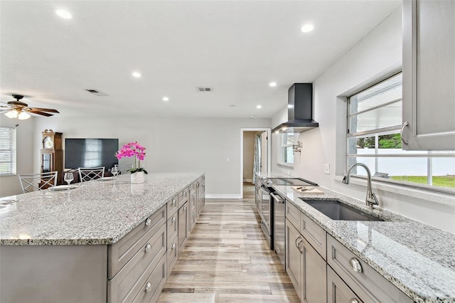 446 Eagle Cir, Casselberry, FL 32707 - kitchen with wall chimney range hood, light wood-style floors, a spacious island, recessed lighting, and light stone countertops