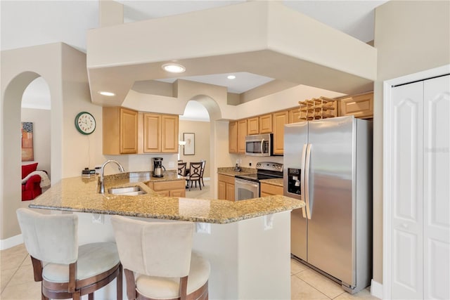 886 Suffolk Pl, Davenport, FL 33896 - kitchen featuring stainless steel appliances, arched walkways, light brown cabinetry, a peninsula, and light tile patterned floors