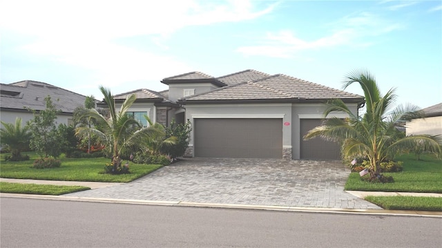 4957 Seafoam Trl, Bradenton, FL 34211 - view of front of home featuring a garage, stucco siding, decorative driveway, a front yard, and a tiled roof