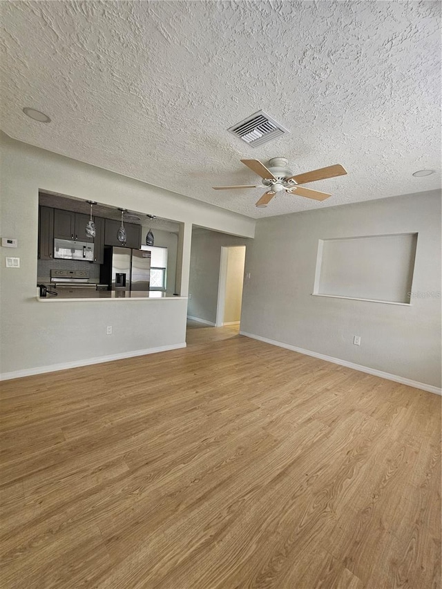 7001 60th St N, Pinellas Park, FL 33781 - unfurnished living room with light wood-type flooring, a textured ceiling, and a ceiling fan