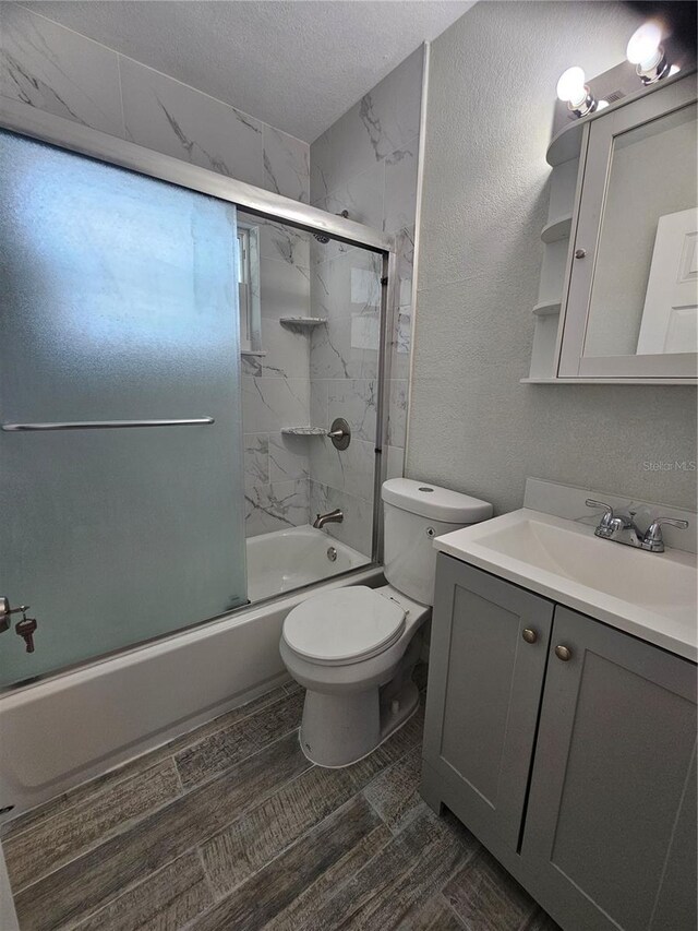 7001 60th St N, Pinellas Park, FL 33781 - bathroom featuring vanity, shower / bath combination with glass door, a textured ceiling, and a textured wall