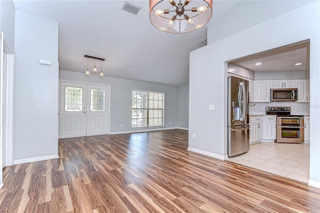 512 Pinewalk Dr, Brandon, FL 33510 - unfurnished living room with a chandelier, light wood-style floors, and vaulted ceiling