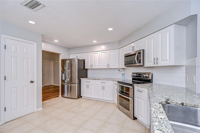 512 Pinewalk Dr, Brandon, FL 33510 - kitchen with appliances with stainless steel finishes, white cabinets, tasteful backsplash, light stone counters, and recessed lighting