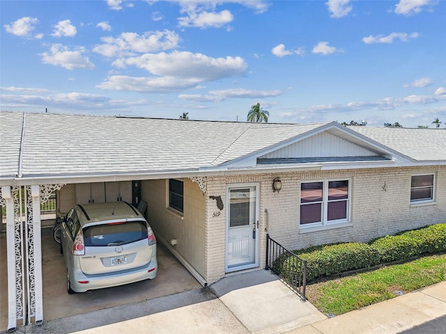 12400 Park Blvd Unit 519, Seminole, FL 33772 - view of front facade featuring a shingled roof, brick siding, a carport, and concrete driveway