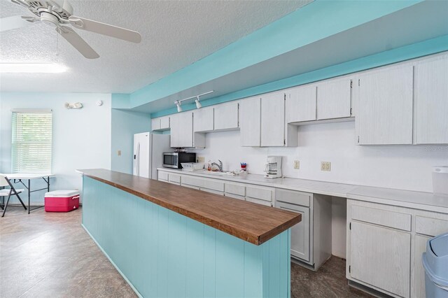 12400 Park Blvd Unit 519, Seminole, FL 33772 - kitchen with stainless steel microwave, white fridge with ice dispenser, ceiling fan, a textured ceiling, and rail lighting
