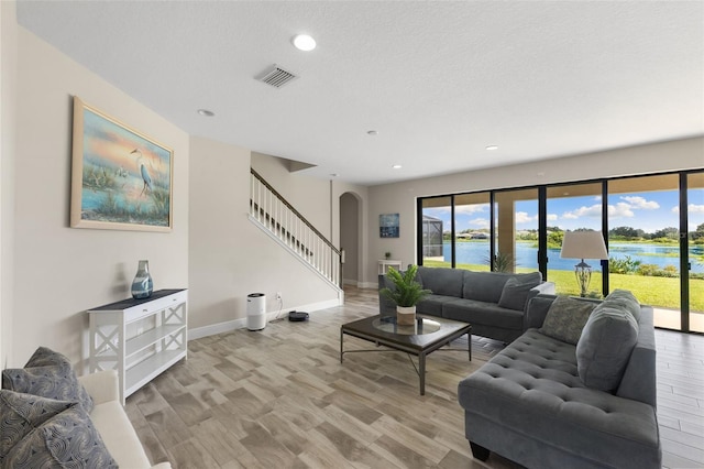 12821 Satin Lily Dr, Riverview, FL 33579 - living area featuring arched walkways, stairway, healthy amount of natural light, light wood-style floors, and recessed lighting