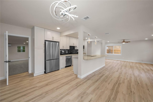 4441 16th St N, Saint Petersburg, FL 33703 - kitchen with appliances with stainless steel finishes, a chandelier, white cabinetry, light wood-type flooring, and recessed lighting