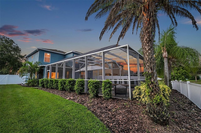 12424 White Bluff Rd, Hudson, FL 34669 - back of house at dusk with a fenced backyard and a lanai