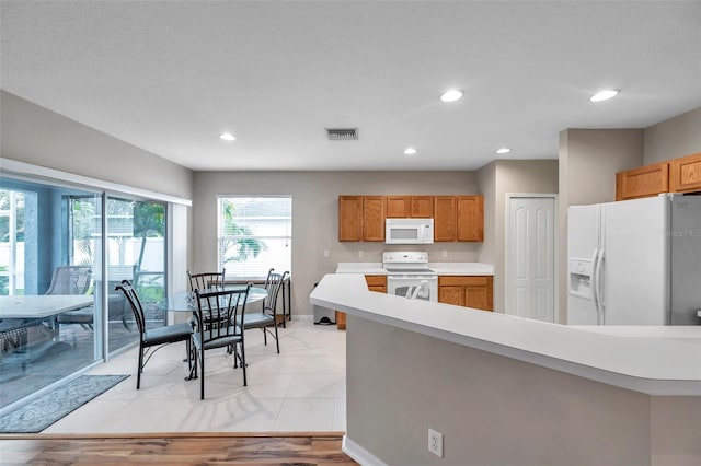 12424 White Bluff Rd, Hudson, FL 34669 - kitchen featuring white appliances, light countertops, recessed lighting, and brown cabinetry