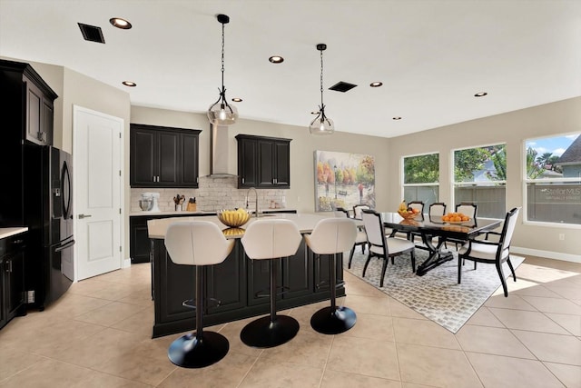 2120 Gwynhurst Blvd, Wesley Chapel, FL 33543 - kitchen with dark cabinets, freestanding refrigerator, light countertops, decorative backsplash, and wall chimney range hood
