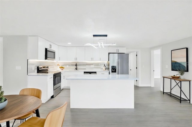 7835 Wallaba Ln, New Port Richey, FL 34653 - kitchen featuring stainless steel appliances, light countertops, a center island, and light wood-type flooring