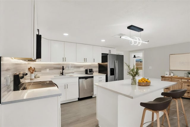 7835 Wallaba Ln, New Port Richey, FL 34653 - kitchen with stainless steel appliances, light wood-style floors, tasteful backsplash, a center island, and recessed lighting