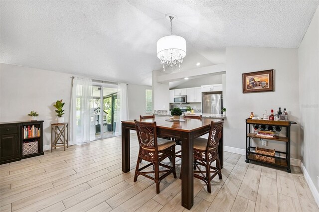 602 Timber Bay Cir W, Oldsmar, FL 34677 - dining space featuring vaulted ceiling, a textured ceiling, a chandelier, and light wood-style floors