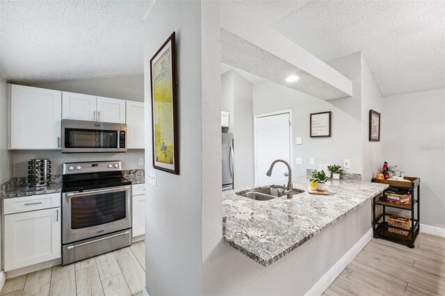 602 Timber Bay Cir W, Oldsmar, FL 34677 - kitchen featuring appliances with stainless steel finishes, a textured ceiling, lofted ceiling, light stone counters, and white cabinets