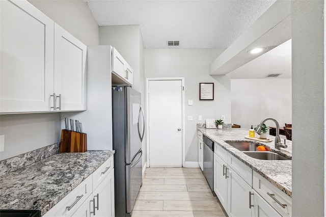 602 Timber Bay Cir W, Oldsmar, FL 34677 - kitchen featuring stainless steel appliances, light stone counters, white cabinets, light wood finished floors, and a textured ceiling