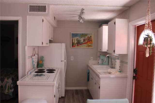 6800 Sunset Way Unit 1708, St Pete Beach, FL 33706 - kitchen with tile countertops, white cabinets, wood finished floors, and track lighting