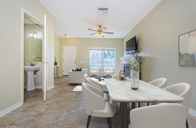 1241 Redondo Way, Wesley Chapel, FL 33543 - dining space featuring a ceiling fan, light stone finish floors, and a glass covered fireplace