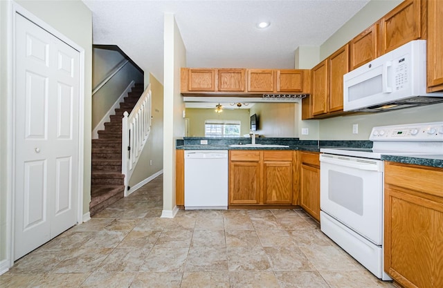 1241 Redondo Way, Wesley Chapel, FL 33543 - kitchen featuring white appliances, dark countertops, brown cabinets, a ceiling fan, and a textured ceiling