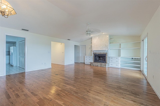 739 Chesapeake Dr, Tarpon Springs, FL 34689 - unfurnished living room featuring ceiling fan, wood finished floors, a large fireplace, lofted ceiling, and a chandelier