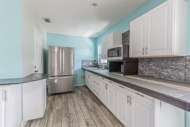739 Chesapeake Dr, Tarpon Springs, FL 34689 - kitchen featuring stainless steel appliances, dark countertops, white cabinetry, tasteful backsplash, and light wood finished floors