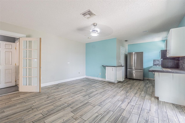 739 Chesapeake Dr, Tarpon Springs, FL 34689 - kitchen with freestanding refrigerator, light wood-type flooring, dark countertops, a ceiling fan, and a textured ceiling