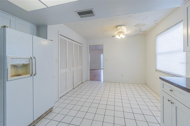 739 Chesapeake Dr, Tarpon Springs, FL 34689 - kitchen featuring white fridge with ice dispenser, ceiling fan, white cabinetry, light tile patterned floors, and dark countertops