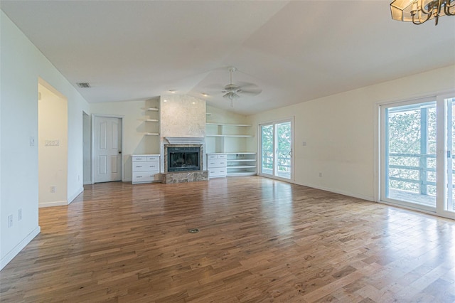 739 Chesapeake Dr, Tarpon Springs, FL 34689 - unfurnished living room with wood finished floors, ceiling fan, vaulted ceiling, a fireplace, and a chandelier