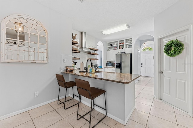 10409 Glen Willow Ln, Tampa, FL 33647 - kitchen featuring appliances with stainless steel finishes, wall chimney range hood, light tile patterned floors, open shelves, and arched walkways