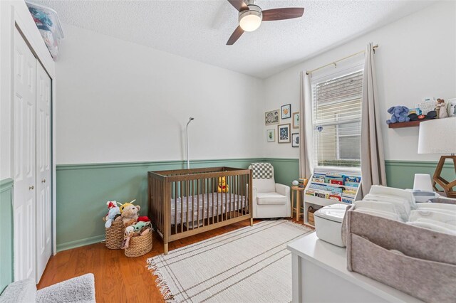 10409 Glen Willow Ln, Tampa, FL 33647 - bedroom featuring a textured ceiling, a closet, a crib, wood finished floors, and a ceiling fan