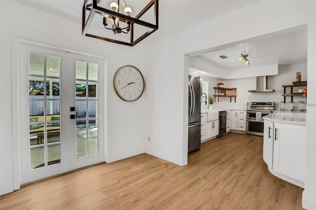 1320 Dixie Ln S, Saint Petersburg, FL 33707 - kitchen featuring stainless steel appliances, wall chimney exhaust hood, open shelves, a chandelier, and decorative backsplash