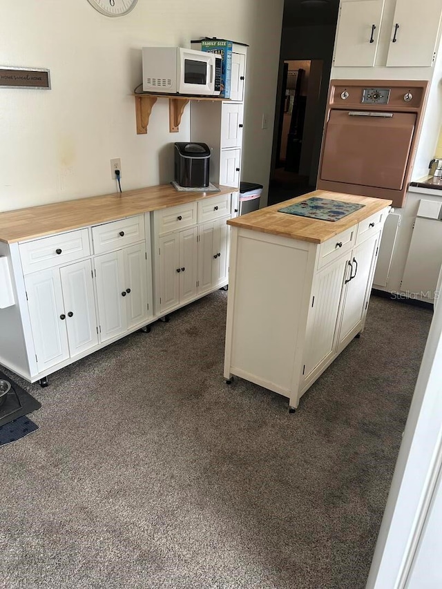 4917 99th St N, Saint Petersburg, FL 33708 - kitchen featuring wood counters, white microwave, oven, white cabinetry, and a kitchen island