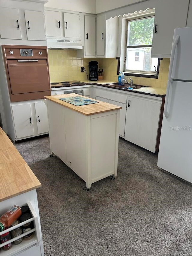 4917 99th St N, Saint Petersburg, FL 33708 - kitchen featuring oven, butcher block counters, freestanding refrigerator, under cabinet range hood, and decorative backsplash