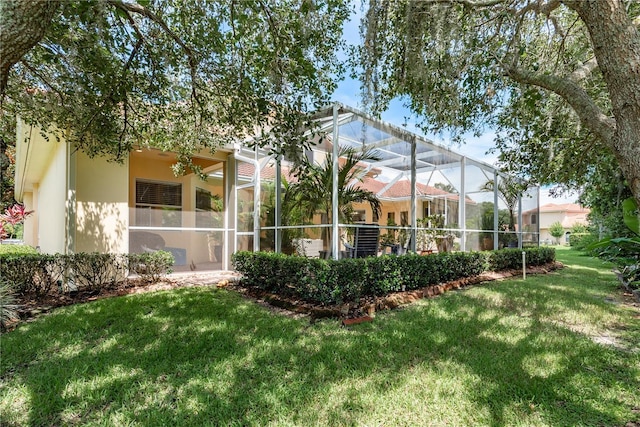 3042 Wentworth Way, Tarpon Springs, FL 34688 - rear view of house with a lawn, stucco siding, and glass enclosure